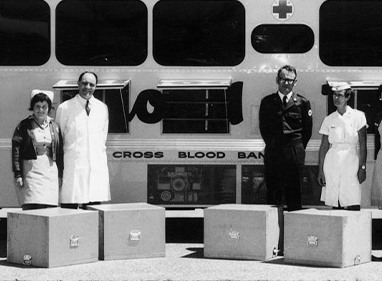 black and white historical photograph of donor staff standing in front of a bus