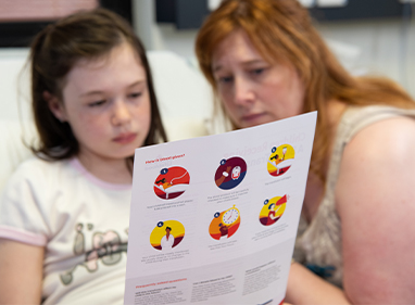a child and parent are reading an information sheet